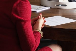 a photo of mary russell's arm wearing a red suit and gold bracelets