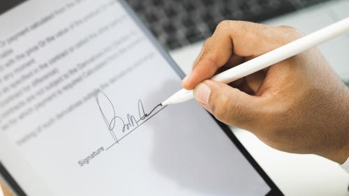 a photo of a hand signing a contract on a tablet with a digital pen