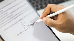 a photo of a hand signing a contract on a tablet with a digital pen