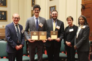 a photo of mac newton (left) and isaac keller (right) holding their awards with competition judges