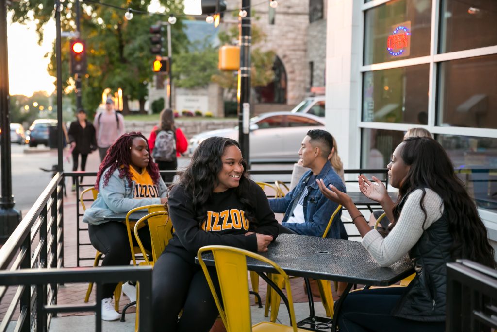 a group of students wearing mizzou gear eating at a columbia restaurant