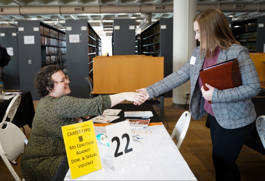 two women shaking hands at a career expo